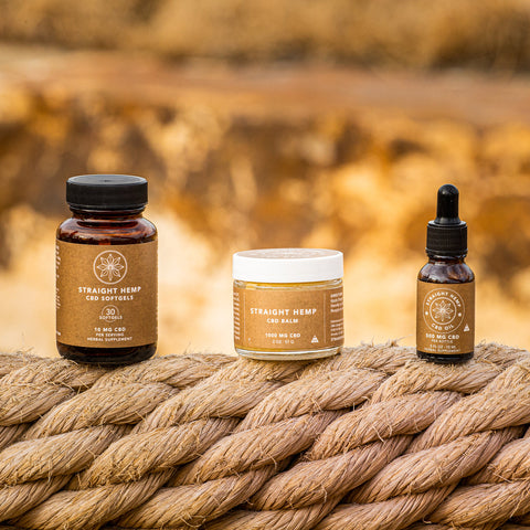 Straight Hemp CBD Softgels, CBD Balm and full spectrum CBD Oil standing on a rope outdoors